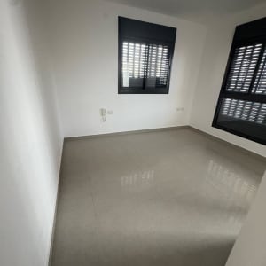 חדר ריק עם רצפת אריחים וחלונות עם תריסים סגורים