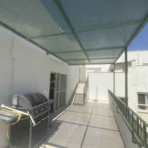 מרפסת עם גג מתכת וגריל גז