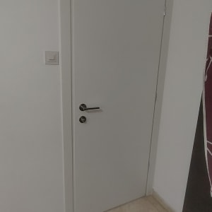 דלת לבנה עם ידית מתכת על רצפת אריחים
