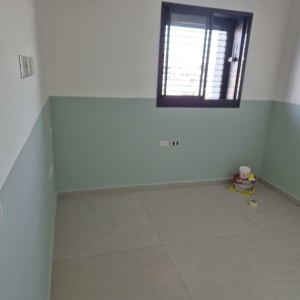 חדר צבוע עם קירות בצבע ירוק וכלי צבע על הרצפה