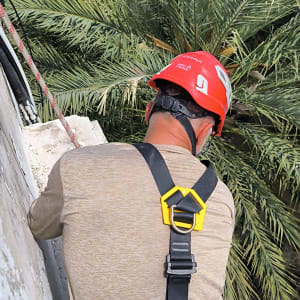 אדם עם קסדה רותם חבל על קיר בטון