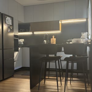 מטבח מודרני עם מקרר, כיור, וכיסאות בר שחורים