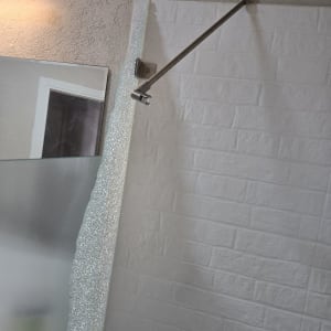 מוט מתכת מותקן על קיר עם אריחים לבנים