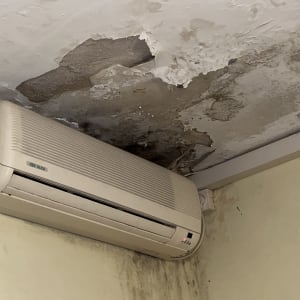 תקרה מתקלפת עם סימני רטיבות מעל מזגן