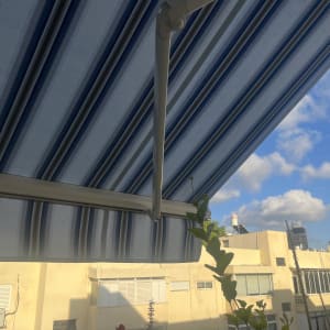 סוכך זרועות מותקן על מרפסת עם שמיים כחולים