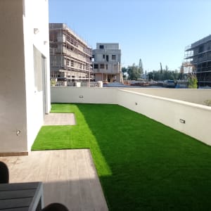 מרפסת עם דשא סינתטי ובניינים בבנייה