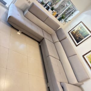 ספה אפורה גדולה בחדר מגורים עם חלון ותמונות על הקיר