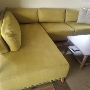 ספה ירוקה עם כרית לבנה ליד שולחן עץ