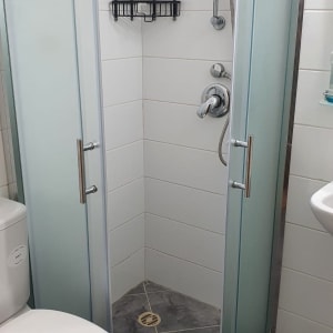 shower area with glass doors and metal showerhead