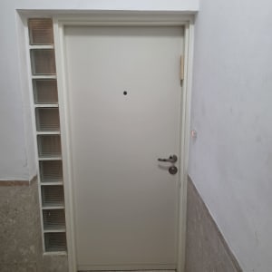 דלת לבנה עם ידית מתכת בקיר לבן