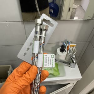 צינורות גמישים ליד כיור בחדר אמבטיה