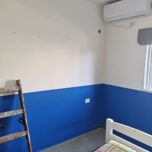 סולם וחדר עם קיר כחול ולבן ומזגן