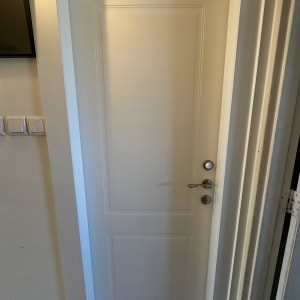 דלת לבנה עם ידית מתכת וכפתור נעילה