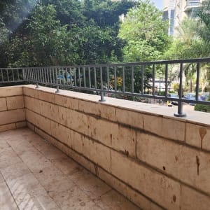 מעקה מתכת אפור על מרפסת אבן