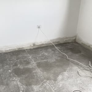 קיר צבוע עם רצפה מוכתמת וחוט חשמל