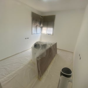 חדר מכוסה בניילון לקראת צביעה, כולל רהיטים ושטח הרצפה.