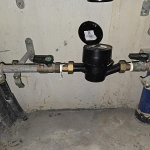 מד מים וצנרת מותקנים על קיר בטון