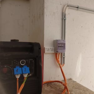 גנרטור עם כבלים כתומים ושקעי חשמל על קיר