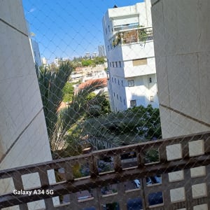 רשת הגנה על מרפסת עם נוף לבניינים ועצים