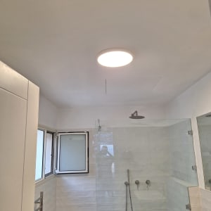 חדר אמבטיה עם מקלחון ותאורה עליונה