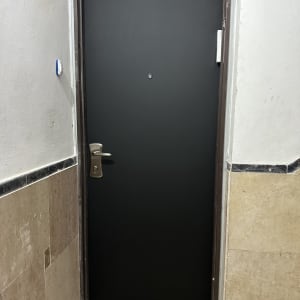 דלת שחורה עם ידית מתכת בקיר לבן