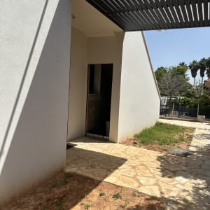 דלת פתוחה בקיר חיצוני עם שביל אבן