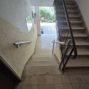 גרם מדרגות עם מעקה מתכת וקיר לבן