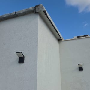 קיר חיצוני עם איטום על הגג ושני פנסי קיר.