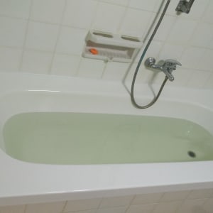 אמבטיה לבנה עם מים, ברז ומקלחת יד