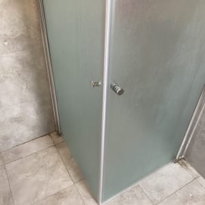 מקלחון פינתי עם זכוכית חלבית ומנגנון הזזה בחדר רחצה