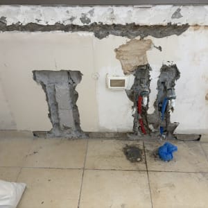 עבודות חציבה והתקנת צנרת מים חדשה בקיר במהלך שיפוץ