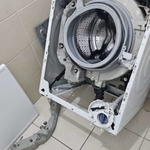 מכונת כביסה פתוחה עם כלים לתיקון על הרצפה