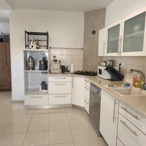 מטבח מסודר עם ארונות לבנים ומכשירי חשמל