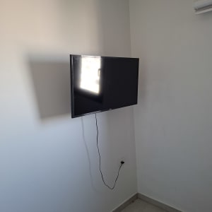 טלוויזיה תלויה על קיר עם כבל חשמל