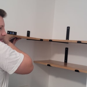 אדם מתקין מדף עם פלס ביד