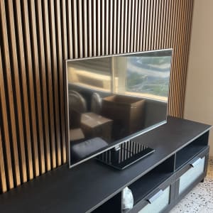 טלוויזיה על שידה מול קיר עץ