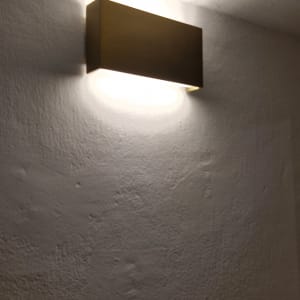 מנורת קיר מוארת על קיר לבן