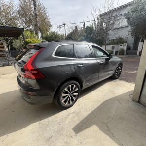 רכב חונה בחניה ליד בית עם עצים ברקע