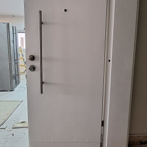 דלת לבנה עם ידית מתכת ארוכה ומנעול