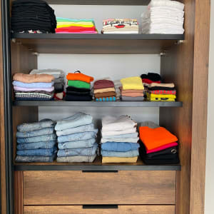 בגדים מקופלים בארון עץ עם מדפים ומגירות