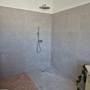 מקלחת חדשה עם אריחים אפורים וראש מקלחת מותקן