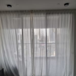 וילון לבן תלוי על חלון בחדר