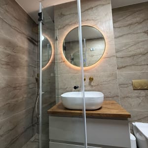 שיפוץ חדר אמבטיה עם כיור עגול ומראה מוארת