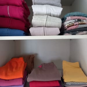 בגדים מקופלים בצבעים שונים על מדפים בארון