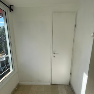 קיר גבס לבן עם דלת לבנה וחלון בצד