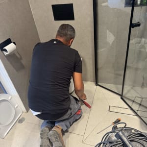 אדם עובד בחדר אמבטיה עם כלים על הרצפה