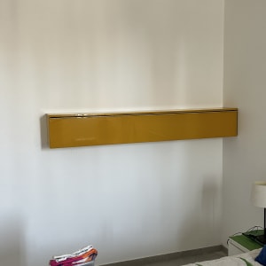 ארון צהוב מותקן על קיר לבן בחדר שינה