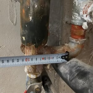 צינור מתכת עם מדידה על רקע קיר בטון