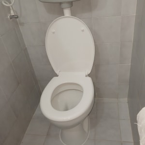 אסלה בחדר שירותים עם אריחי קרמיקה אפורים