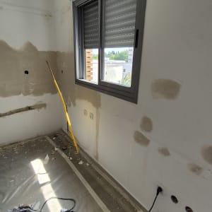 חדר בשיפוץ עם קירות מטויחים וכלי עבודה